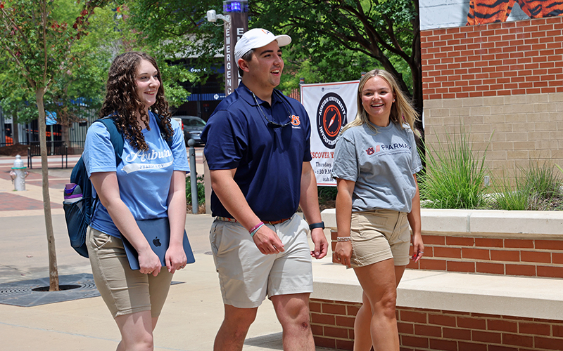 Three smiling students walking across campus