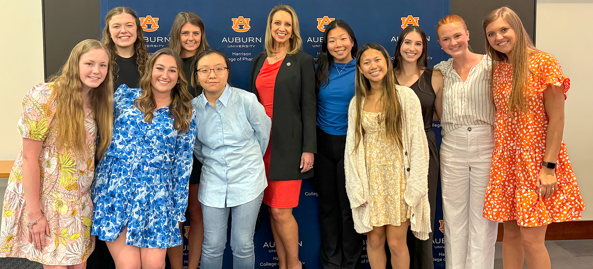 Students stand together with the Dean in front of photo backdrop