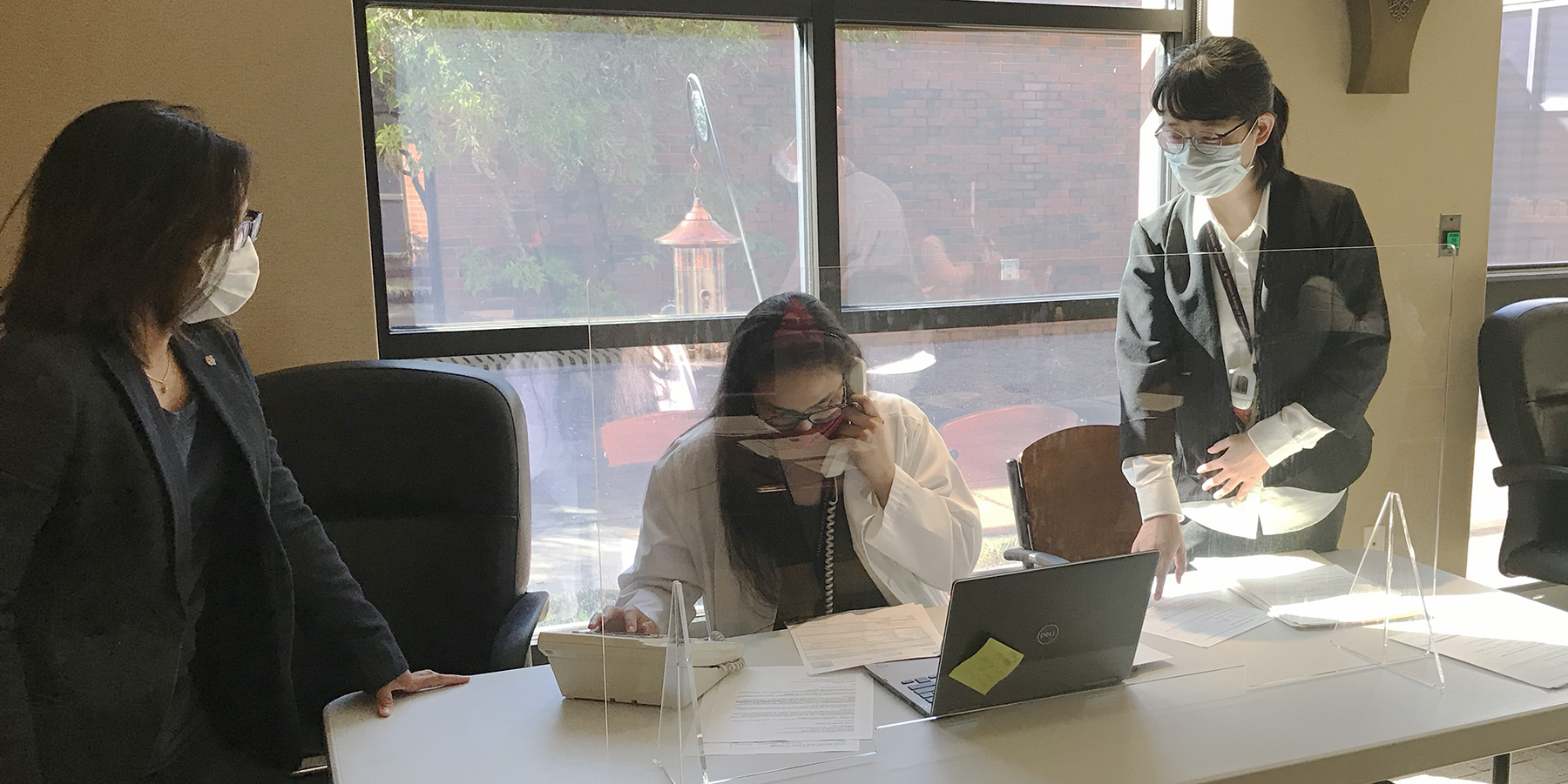 Two people oversee student counselor on the phone
