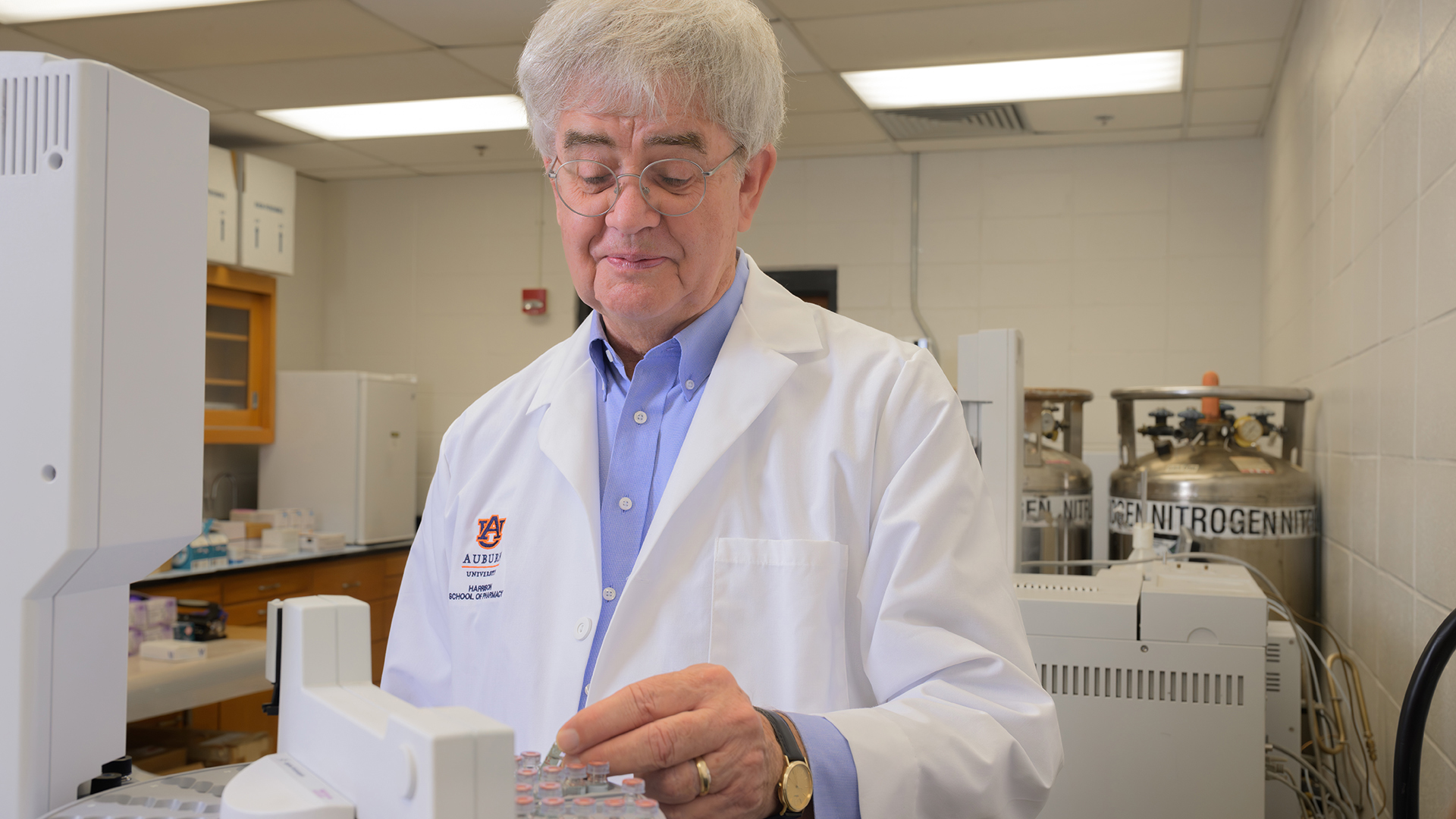 Clark stands over a piece of scientific equipment